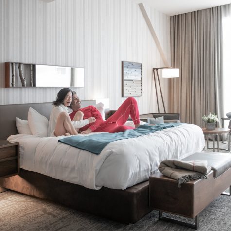 A couple laughs in bed for a romantic getaway at Edgewood Tahoe Resort.
